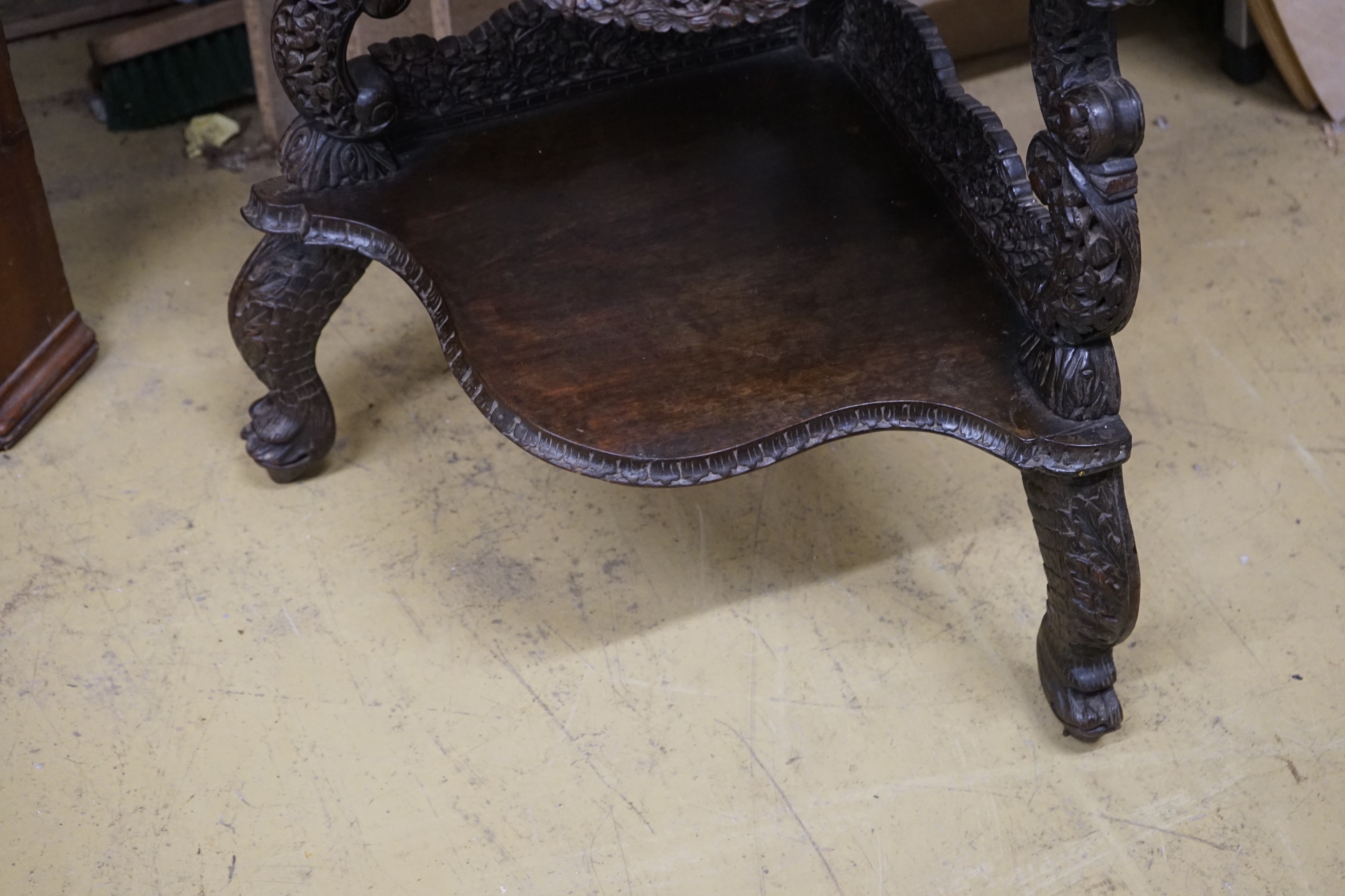A 19th century Burmese carved hardwood serpentine corner whatnot, width 60cm, depth 42cm, height 153cm